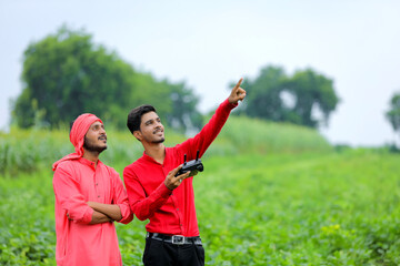 Naklejka premium Indian farmer and agronomist using drone at agriculture field