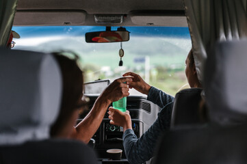 People go on vacation. Friends car trip to the mountains. POV at summer day on a country road, having fun driving the empty highway on tour journey. passenger serves a drink to the driver.