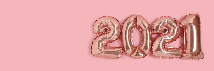 Banner with 2021 made from rose gold color balloons on a pink background with place for text.