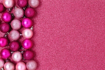 Christmas balls frame on a pink glittering background. Festive monochrome texture with place for text.