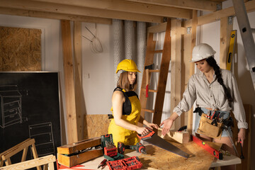 Two girls start in the workshop preparing the tools to start the working day on the construction...