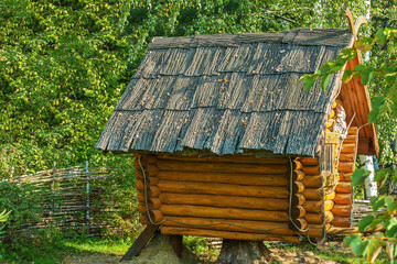 Decorative hut made of logs behind a wicker fence;