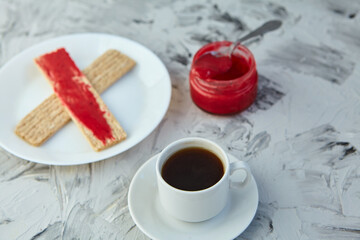 Crispbread with jam for Breakfast on a gray background. A jar of Fresh Honey with foam is next to a Cup of coffee. A minimum of calories. proper nutrition