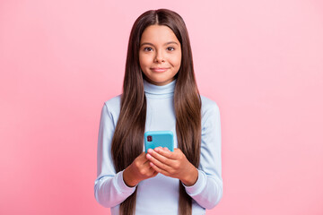 Portrait of pretty cheery brown-haired girl holding in hands using gadget isolated over pink pastel color background