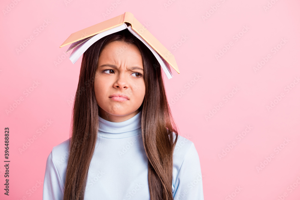 Wall mural Close-up portrait of pretty bored lazy brown-haired girl wearing book on head looking aside copy space isolated over pink pastel color background