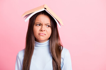 Close-up portrait of pretty bored lazy brown-haired girl wearing book on head looking aside copy...