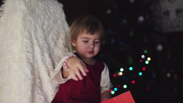 a child in red clothes is sitting waiting for the new year. the concept of celebrating Christmas at midnight. holiday costume. a girl writes a letter to Santa Claus. wish list