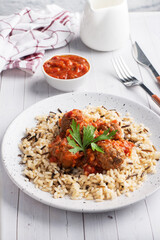 Beef meatballs and brown rice on a plate. Ready made portioned dish meat with garnish.