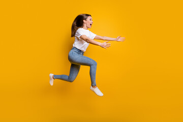 Fototapeta na wymiar Full length body size side profile photo of young girl jumping high embracing copyspace isolated on vivid yellow color background