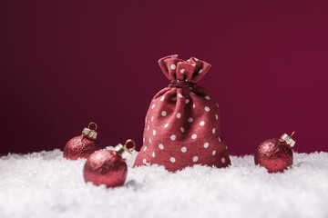 Sack of presents and Christmas decoration in snow over pink background
