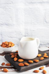 Almond milk in ceramic milk jug on a gray background. Copy space.