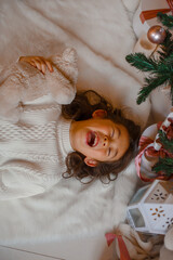 Fototapeta na wymiar little Asian girl lying on her back near the Christmas tree, top view smiling Christmas, new year