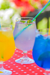 Three ice soft drinks with soda water, refreshing summer beverage. Alcohol cocktail with ice in a glass outside.