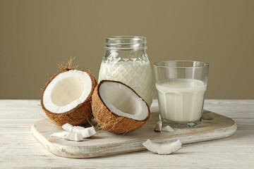 Board with fresh coconut and coconut milk on wooden background