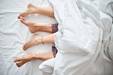 Fototapeta na wymiar Loving young couple with bare feet lying in bed