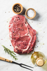 Sliced raw ribeye steak on white kitchen table.