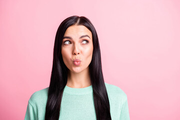 Photo portrait of dreamy female student looking at blank space with pouted lips isolated on pastel pink color background