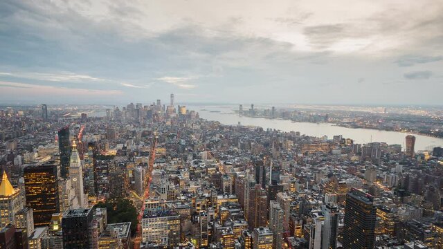 Sunset over New York, the day goes into the night, the clouds float dramatically over the city. Aerial wide video 4k timelapse