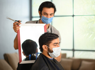 Hair dresser showing mirror to the customer after giving him a haircut	