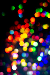 Christmas tree garland light. Colorful bokeh blurry decor on black background. Holiday wallpaper...
