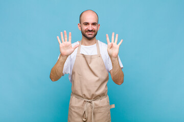 bald man smiling and looking friendly, showing number nine or ninth with hand forward, counting down