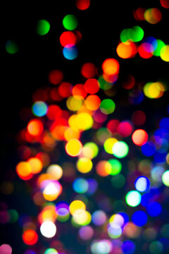 Christmas tree garland light. Colorful bokeh blurry decor on black background. Holiday wallpaper night glowing. City light dark overlay defocused holographic ray. Abstract blurred clipart