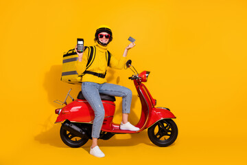 Full length body size photo of female courier terminal bank card smiling on motorbike isolated vibrant yellow color background