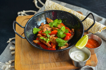 Vegetables and meat in wok pan served with lavash bread and different kinds of sauce. Close up.