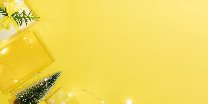 Xmas new normal workspace concept in yellow color- notepad on 2021, small Xmas tree, DIY gift box, protective face mask.