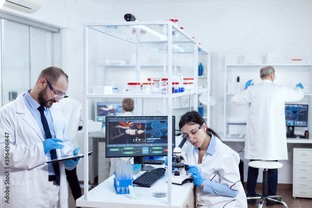 Poster young scientists with tablet pc and microscope making tests in busy lab. team of researchers doing p