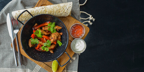 Vegetables and meat in wok pan served with lavash bread and different kinds of sauce. Close up.