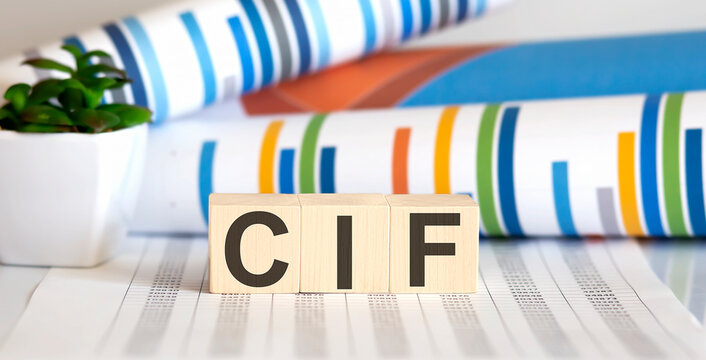 Three wooden cubes with letters CIF , on white table with charts