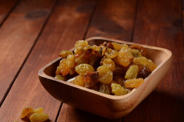 Heap of yellow Raisins, in a wooden bowl.  Bowl with dried golden raisins . Dried Grapes.