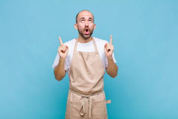 bald man feeling awed and open mouthed pointing upwards with a shocked and surprised look