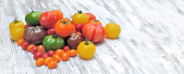 heap of colorful and various tomatoes on white wooden table