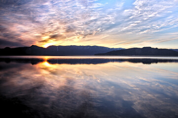 Obraz premium カルデラ湖の夕暮れ。外輪山の彼方に沈む夕陽の雄大な風景。