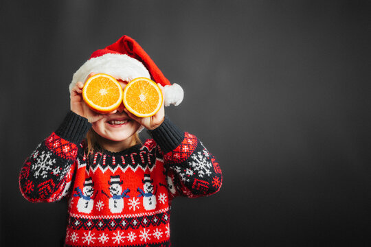 Child Looking At Christmas Present Through Orange On Black Background