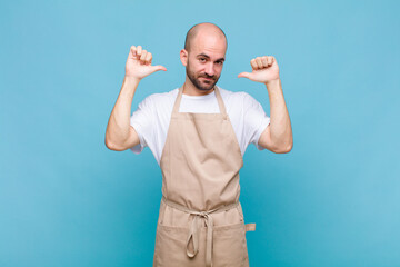 bald man feeling proud, arrogant and confident, looking satisfied and successful, pointing to self
