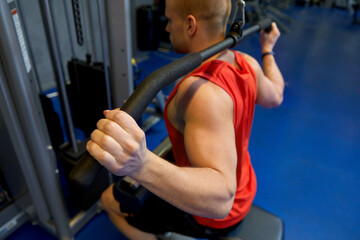 sport, fitness and bodybuilding concept - close up of man exercising with cable machine in gym