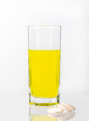 A large, white tablet with dissolves in a glass of water on a white background. Vitamin C.