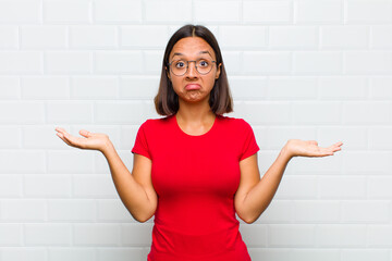 latin woman feeling puzzled and confused, doubting, weighting or choosing different options with...