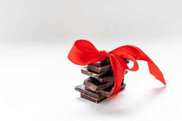 Home made dark chocolate bar with red bow on white background.