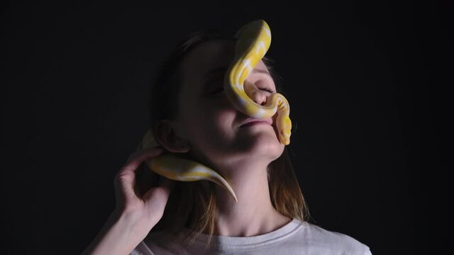Slow motion shooting of woman with python albino crawling on her face