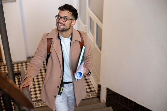 A Portrait Of A Young Smiling Student Walking Up The Stairs To The Apartment.