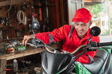 Fototapeta na wymiar mechanic in a wearpack checks the engine throttle of the dirt bike in the garage