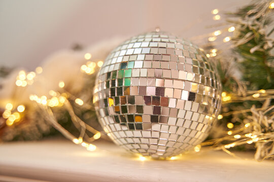 Mirror Ball Disco With New Year's Decorations Lies On A White Fireplace