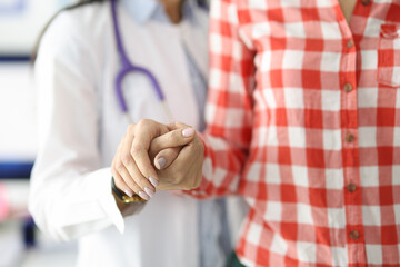 Doctor supporting patient by hand and helping to go to clinic