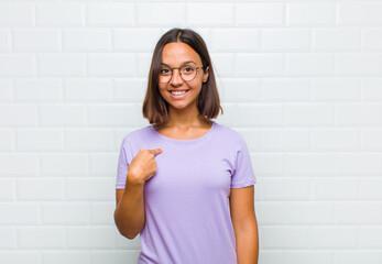 latin woman looking happy, proud and surprised, cheerfully pointing to self, feeling confident and...