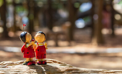 A doll in the shape of a ladybug stands on a wood in the woods, as if talking to a companion