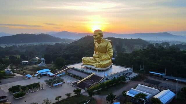 4k The golden image of the Luang Pu Thuat, the most famous and respected monk in Thailand. Big Golden Statue in mountains at beautiful sunrise in Khao Yai, Korat province Aerial: panning right to left